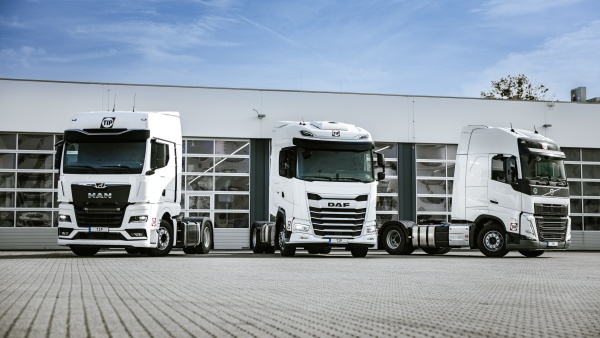 Three white semi-trucks parked in a row