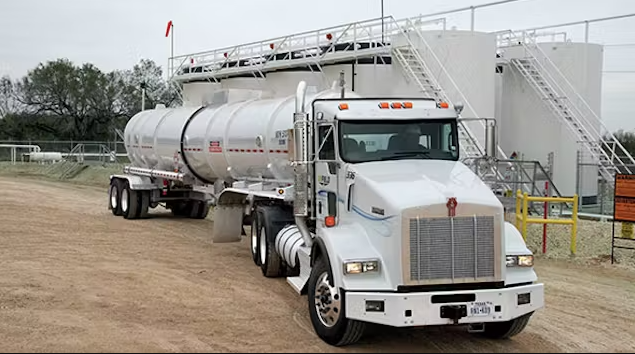 A white tanker truck parked at an industrial facility.